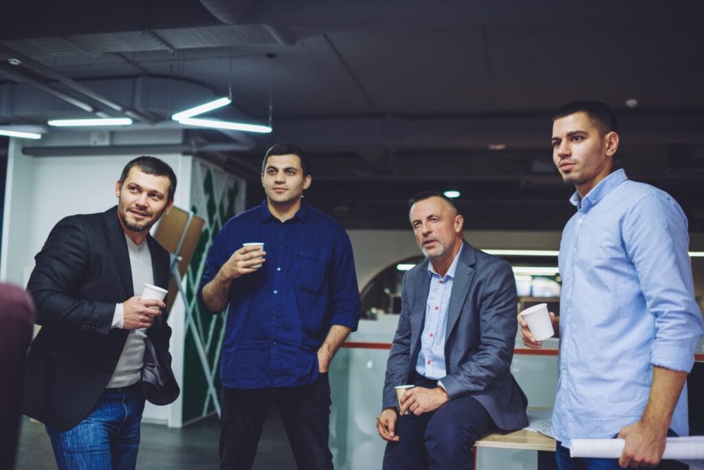 Group of competitive male partners dressed in smart casual clothes spending working time