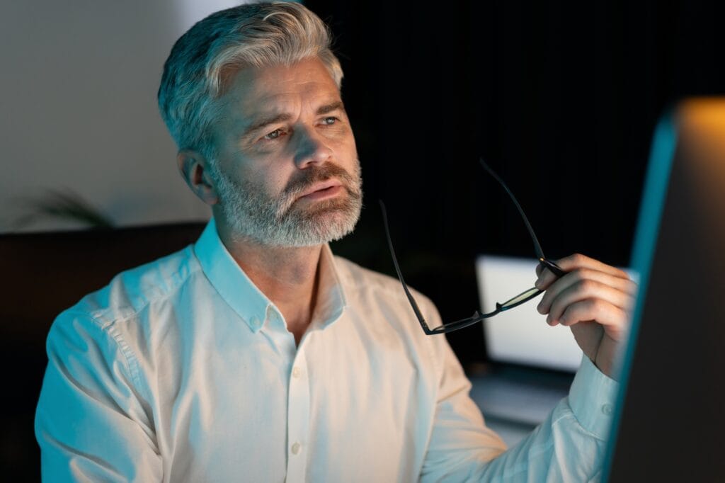Senior Businessman Working Late Night in Office Deep in Thought